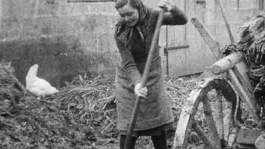 Bäuerin mit Mistgabel auf Misthaufen | Bild: BR Archiv